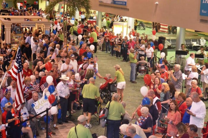 The author accompanies Bob through a crowd welcoming their soldiers home as someone reaches to shake his hand.